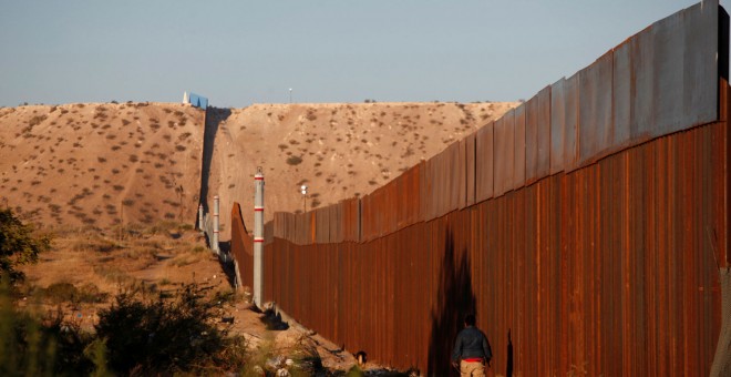 Un hombre pasa por una sección del muro que separa EEUU de México, cerca de Ciudad Juarez. - REUTERS