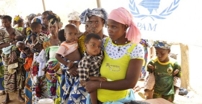 Mujeres y niños hacen cola en un campamento de Burkina Faso. AFP/Ahmed Oioba/Archivo