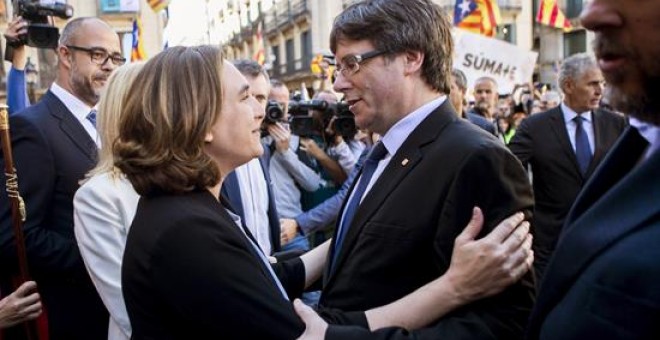 La alcaldesa de Barcelona, Ada Colau (i), saluda al presidente de la Generalitat, Carles Puigdemont (d), durante la concentración de alcaldes en la plaza Sant Jaume de Barcelona, convocada por la AMI y la ACM para protestar por las actuaciones de la Fisca