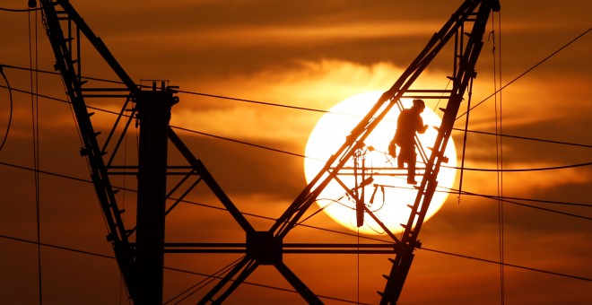 Un operario reparando una torre eléctrica de alta tensión. REUTERS