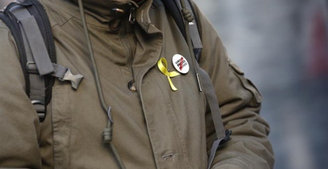 Una persona amb un llaç groc i una xapa que demana la llibertat per als presos polítics. Europa Press.