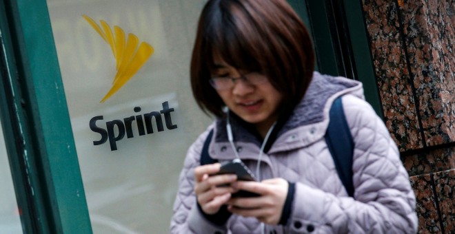 Una mujer maneja su móvil junto a una tienda de Sprint en Nueva York. REUTERS/Brendan McDermid