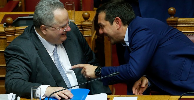 El primer ministro griego, Alexis Tsipras, conversa con el ministro de Exteriores,Nikos Kotzias, durante la moción de censura en el Parlamento griego.-  REUTERS