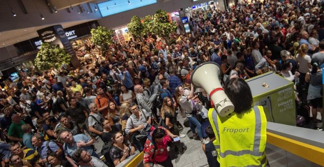 Personal del aeropuerto informa a pasajeros y visitantes mientras esperan a que se termine la evacuación en el aeropuerto de Fráncfort (Alemania), hoy, 7 de agosto de 2018. La evacuación preventiva de una parte de la Terminal 1 del aeropuerto de Fráncfort