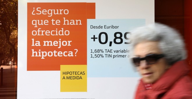 Una mujer pasa junto a una publicidad de hipotecas en una sucursal de Bankinter. REUTERS/Susana Vera