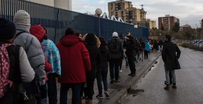 Un agente de policía reparte los turnos de los 80 solicitantes de asilo que serán atendidos en la comisaría de Aluche.- JAIRO VARGAS