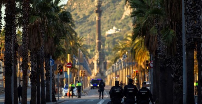 Miembros de las fuerzas de seguridad protegen el paseo de Colón, que aparece desierto, la zona más cercana a la Llotja de Mar de Barcelona. /EFE