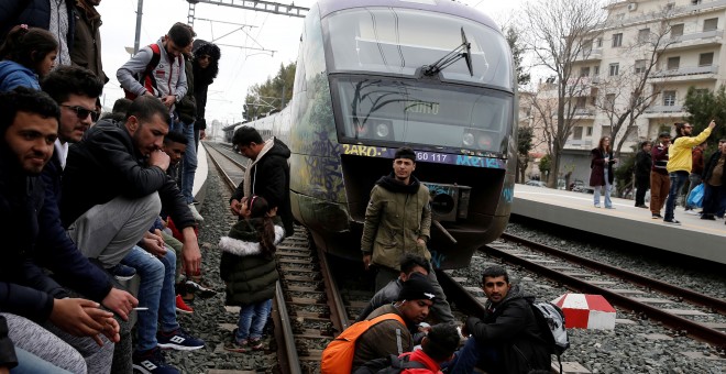 Personas migrantes sentadas en las vías del tren este 5 de abril durante una protesta en Atenas. REUTERS/Costas Baltas