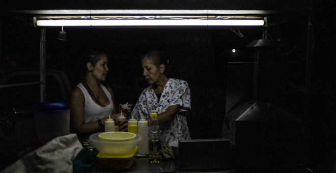 Yugli y su hija Laura atienden su puesto de parrilla en una calle del barrio 23 de Enero de Caracas.- JAIRO VARGAS