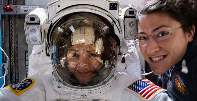 La astronauta Christina Koch (derecha) posa con su compañera de la NASA Jessica Meir (izquierda), que está dentro de un traje espacial verificando su ajuste. / NASA