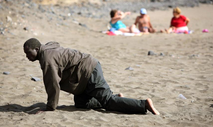 Un inmigrante exhausto llega a la  playa de Fuerteventura, en Canarias, ante la mirada de los turistas (5 de mayo de 2006). REUTERS / Juan Medina