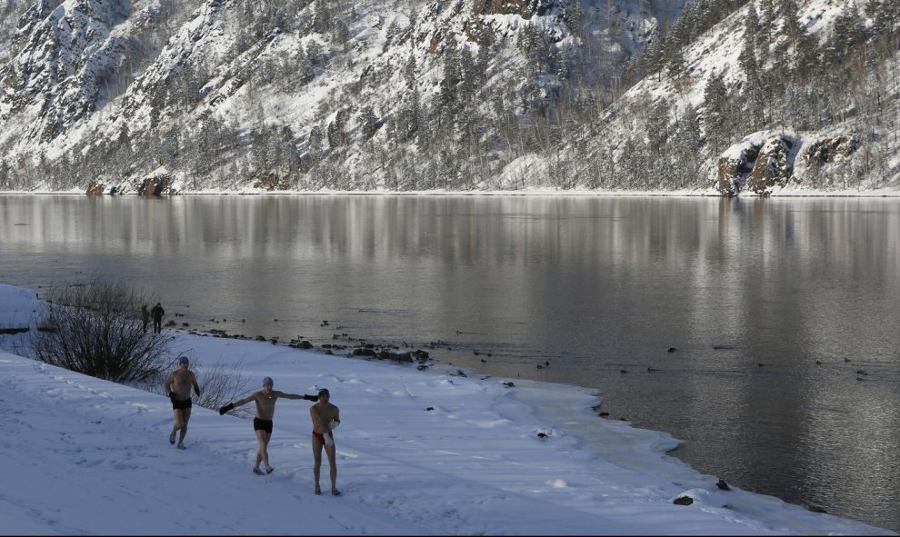 Los miembros de un club de natación calientan en la orilla del río Yenisei antes de su sesión semanal de baño en Divnogorsk, Rusia. REUTERS/Ilya Naymushin