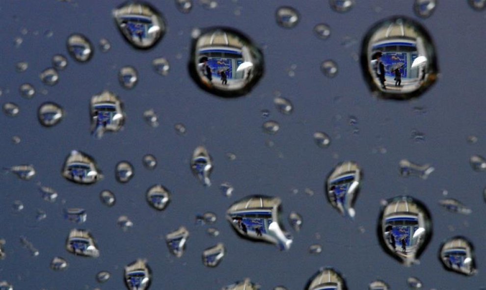 Una imagen rotada 180 grados, muestra gotas de lluvia que reflejan una pantalla que muestra información bursátil en Tokio, Japón. EFE/Franck Robichon