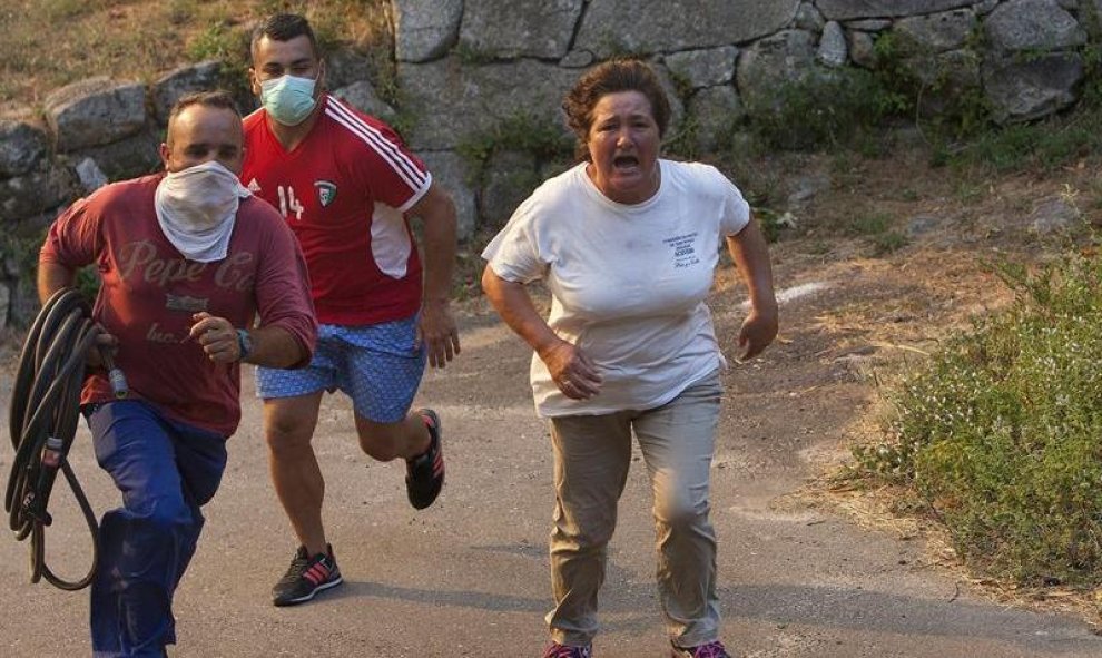 Tres vecinos corren desesperados a apagar el fuego en un pueblo de Pontevedra, que estaba muy próximo a sus casas/EFE