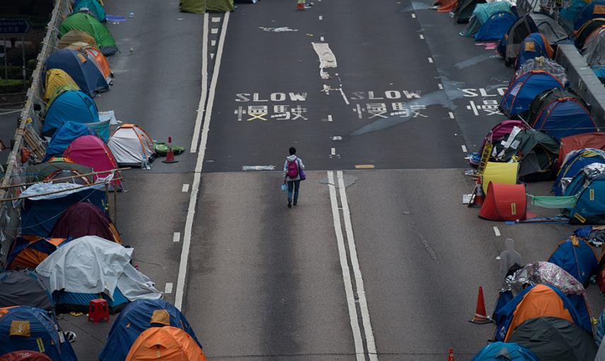 Una mujer camina en un paso elevado en el lugar en el que acampan los manifestantes por la democracia en el distrito Almirantazgo de Hong Kong. // JOHANNES EISELE (AFP)