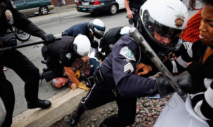 Policías tratan de hacer retroceder a los manifestantes mientras un compañero detiene a un hombre, durante las protestas contra la decisión de la justicia de no acusar a Darren Wilson por la muerte a tiros de Michael Brown. // PATRICK T. FALLON (REUTERS)