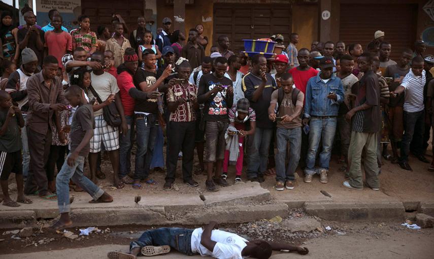 Un grupo de personas observa y fotografía a el cuerpo de una supuesta víctima de ébola en la ciudad de Koidu, en el este de Sierra Leona. /BAZ RATNER (REUTERS)