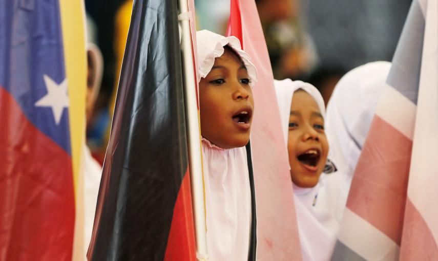 Unas niñas de la provincia indonesia de Aceh cantan y sostienen banderas en la ceremonia para recordar a las víctimas del tsunami de 2004. REUTERS/Beawiharta