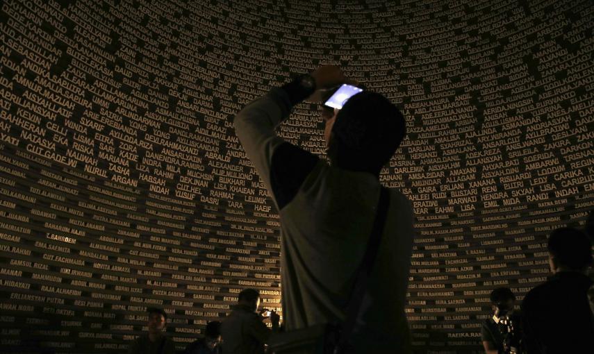 Un visitante toma una fotografía dentro del monumento en Banda Aceh que recoge los nombres de las víctimas del tsunami de 2004.  REUTERS/Beawiharta