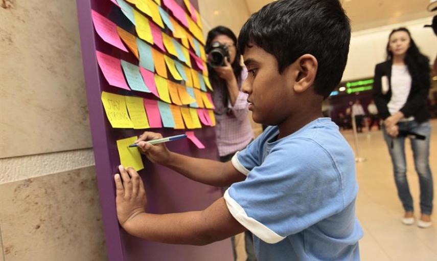 Un niño escribe un mensaje de apoyo a los pasajeros del vuelo QZ 8501 de AirAsia desaparecido, a las puertas de la zona de espera de familiares en el Aeropuerto Changi de Singapur. EFE