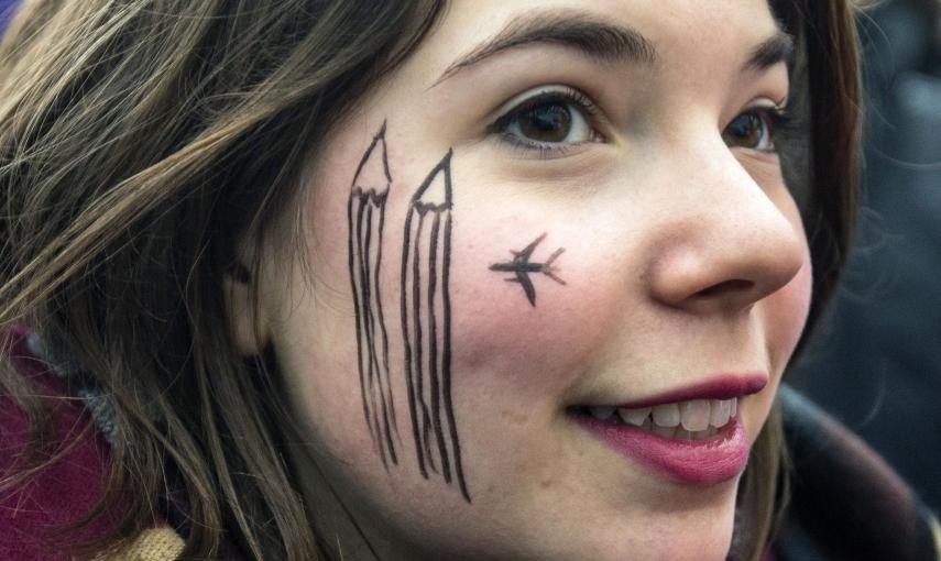 A woman wears a cartoon painting on the face during a silent protest for the victims of the shooting at the Paris offices of weekly newspaper Charlie Hebdo, at the Pariser Platz square in Berlin January 11, 2015. REUTERS/Hannibal Hanschke