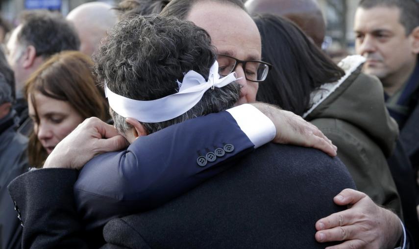 French President Francois Hollande (R) comforts French columnist for Charlie Hebdo Patrick Pelloux as they take part with family members and relatives in a solidarity march (Marche Republicaine) in the streets of Paris January 11, 2015. Hundreds of thousa