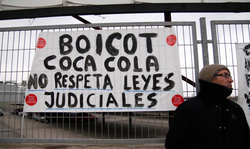 Un empleado de Coca-Cola junto a una pancarta que pide que la empresa acate la sentencia judicial. -JAIRO VARGAS