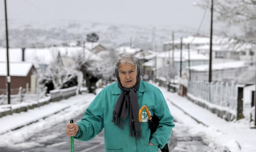 Una mujer camina por una calle de la localidad de Vilariño Frío que amanecía hoy nevado debido al temporal de frío y viento que afecta a Galicia y gran parte de la península. EFE