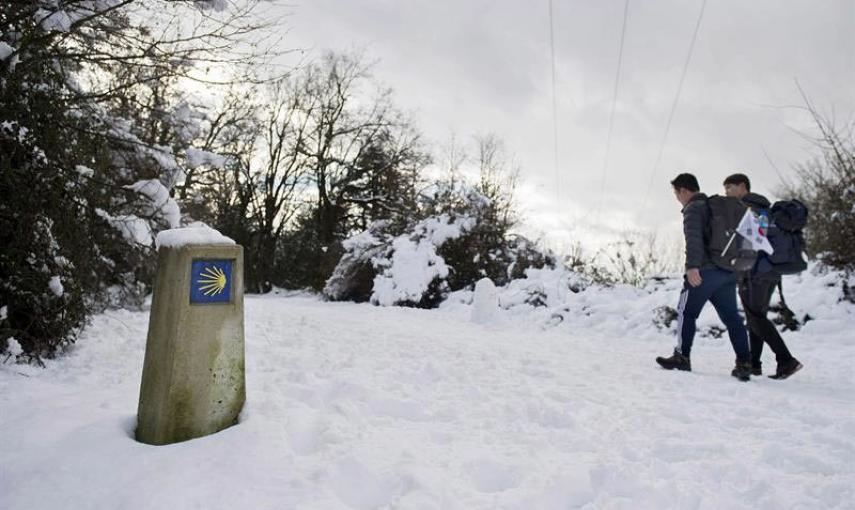 Dos peregrinos coreanos caminan por el Alto de Erro (Navarra) que esta mañana ha amanecido nevado debido al temporal de frío y nieve que azota el norte de la comunidad Foral. EFE/Villar López