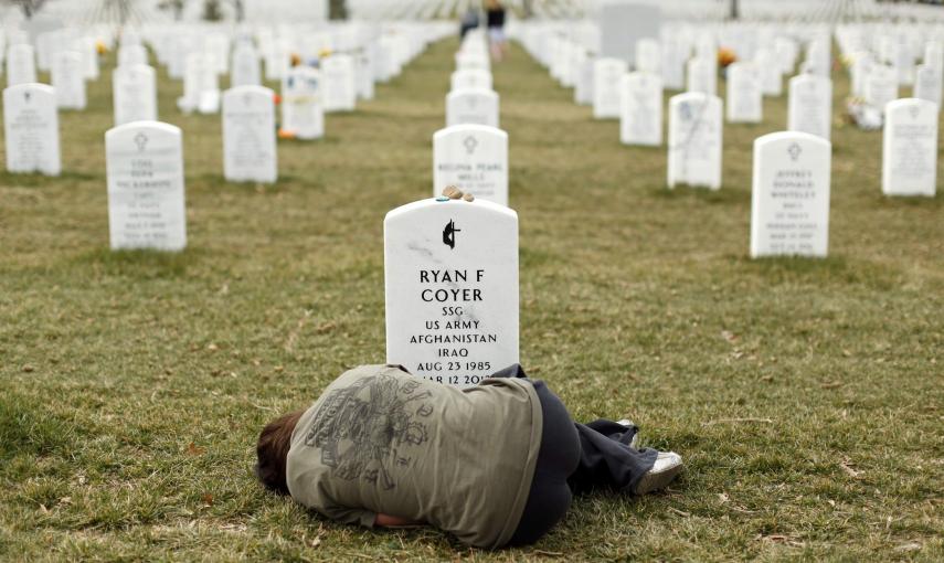 Lesleigh Coyer, de 25 años, tumbado delante de la tumba en el Cementerio Nacional de Arlington de su hermano, Ryan Coyer, que sirvió con el Ejército de EEUU en Irak y Afganistán (11 de marzo de 2013). REUTERS / Kevin Lamarque