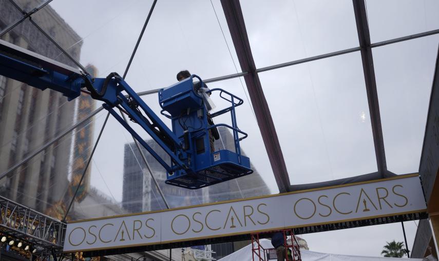 Un trabajador coloca un toldo para proteger de la lluvia la alfombra roja por donde desfilarán los asistentes a la 87ª cereonia de enmtrega de los premios Oscar. REUTERS/Rick Wilking