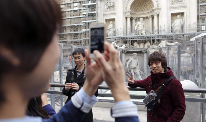 Unos turistas se fotografía junto a la Fontana de Trevi, donde están terminando los trabajos de restauración. REUTERS/Tony Gentile