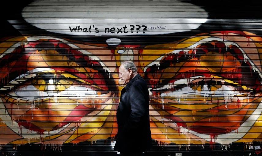 Un hombre camina junto a un graffiti en Atenas (Grecia). /ALKIS KONSTANTINIDIS (REUTERS)