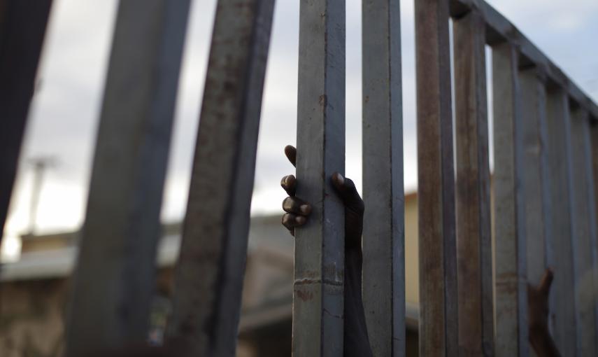 Un haitiano se aferra a un barrote en la frontera con la República Dominicana. / REUTERS