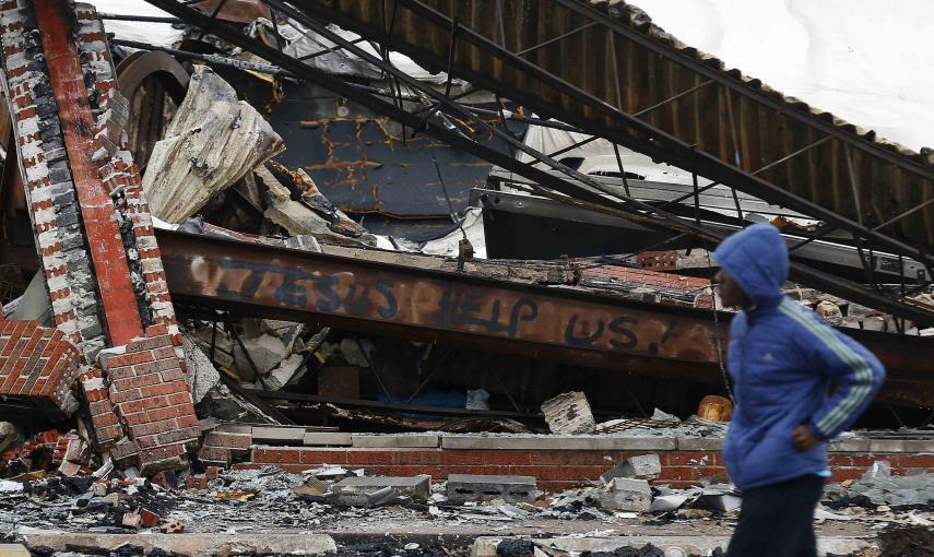 Un hombre pasea junto a un edificio reducido a cenizas en Ferguson. / REUTERS