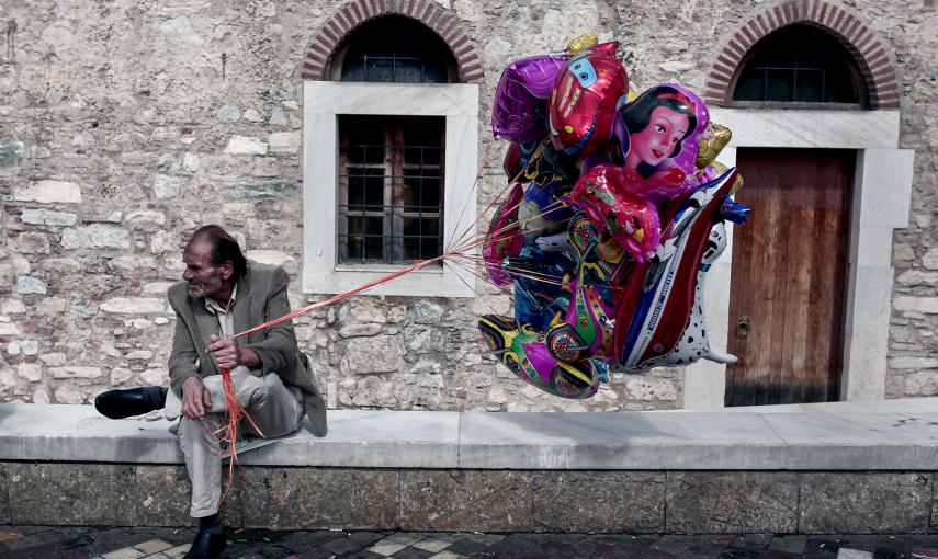 Un hombre vende globos en una plaza de Atenas. / AFP