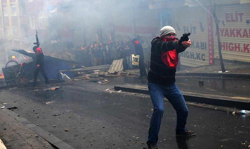 Un hombre apunta su arma frente a la policía durante los disturbios del pasado 11 de Marzo en Estambul. / AFP