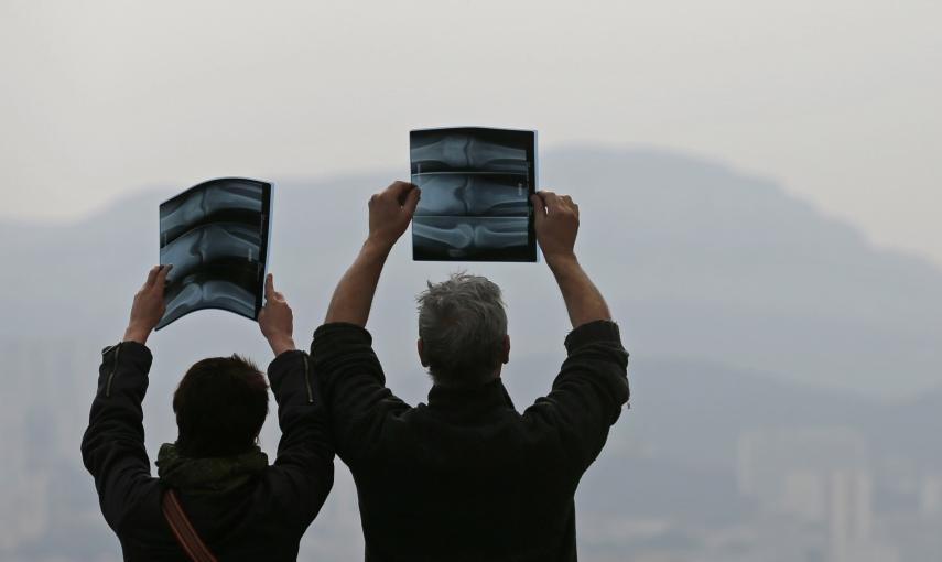 Dos personas en Marsella (Francia) tratan de ver el eclipse parcial de sol a través de unas radiografías. REUTERS/Jean-Paul Pelissier