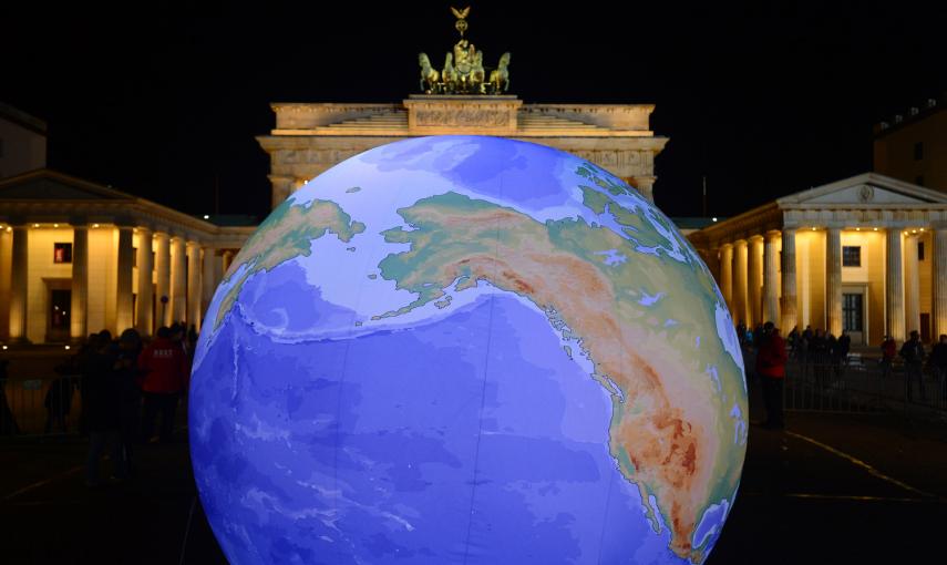 Un globo terráqueo iluminado junto a la Puerta de Brandeburgo. - AFP