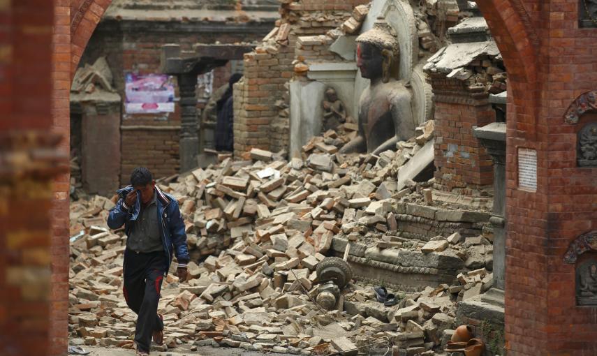 Un hombre llora mientras camina por la calle mientras junto a una estatua de Buda dañada un día después de un terremoto en Bhaktapur, Nepal.- REUTERS / Navesh Chitrakar