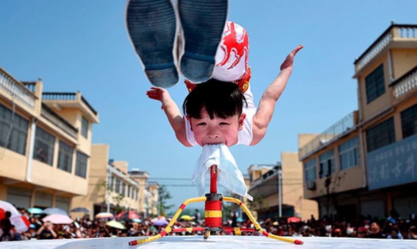 Un acróbata de seis años de edad lleva a cabo un ejercicio durante la apertura de un festival turístico en Bozhou, provincia de Anhui (China).- REUTERS