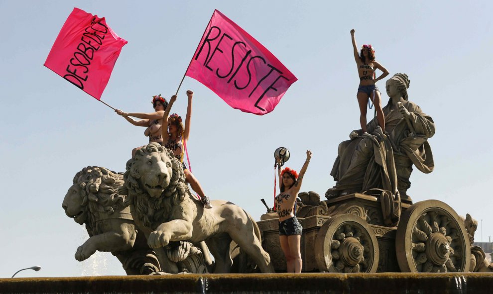 Cuatro activistas de Femen se han encaramado hoy en una acción sorpresa a la fuente de Cibeles para protestar contra la ley mordaza.- EFE/Juan Carlos Hidalgo