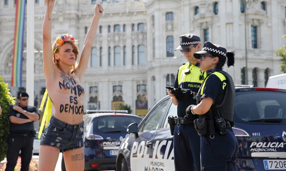 Dos policías municipales observan a las activistas de Femen que se han encaramado hoy en una acción sorpresa a la fuente de Cibeles para protestar contra la ley mordaza.- EFE/Juan Carlos Hidalgo