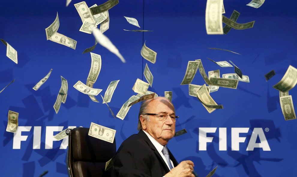 El presidente de la FIFA, Joseph Blatter, bajo una lluvia de billetes que le lanzó el humorista británico Simon Brockin, durante una rueda de prensa para presentar los resultados de la reunión del Comité Ejecutivo de la FIFA en su sede de Zúrich, Suiza.