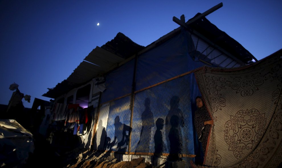 Una mujer palestina se asoma desde un refugio improvisado cerca de su casa, que según testigos, fue destruida por los bombardeos israelíes durante una guerra de 50 días el verano pasado, en la ciudad de Beit Hanoun, en el norte de la Franja de Gaza. REUTE