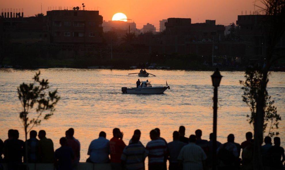 Familiares observan al equipo de rescate buscar víctimas en el río Nilo, al norte de El Cairo, después de que al menos 18 personas murieron cuando un buque de carga golpeó su barco donde celebraban una fiesta. AFP PHOTO / STR