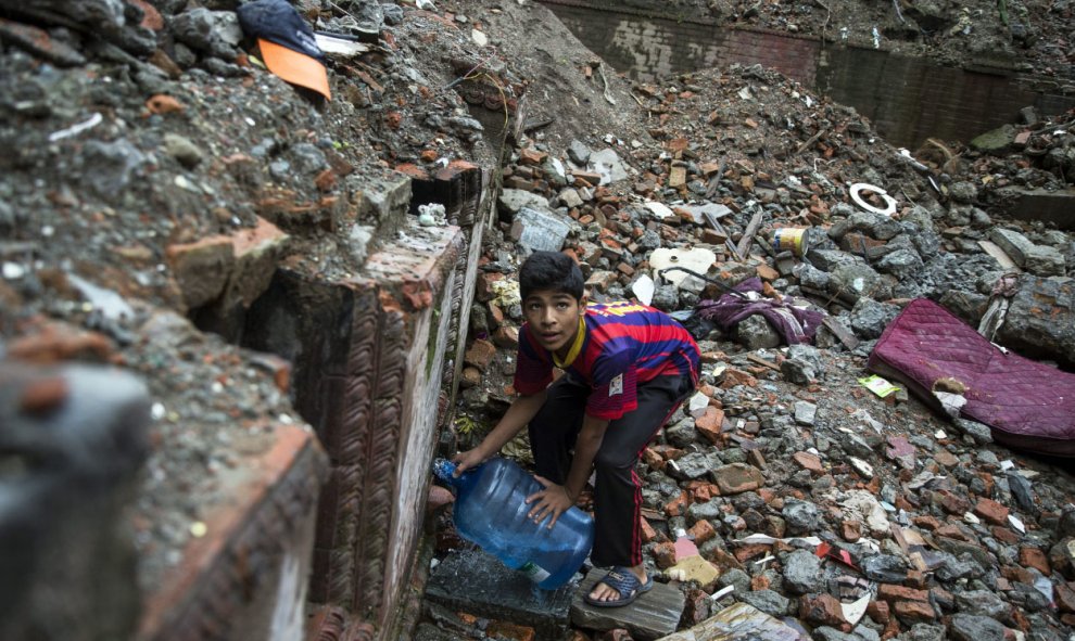 Un niño nepalí vestido con una camiseta del FC Barcelona llena un bidón de agua en Thamel, Katmandú (Nepal) hoy, 23 de julio de 2015. Tras los graves destrozos causados por el terremoto que asoló Nepal el pasado mes de abril los locales se enfrentan a dif