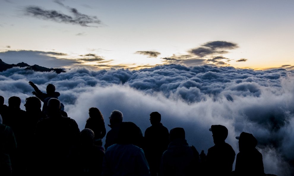 Turistas esperan a la salida del sol sobre el lecho de niebla asentado en la falda de la montaña Eggishorn, de 2.927 metros de altura sobre el nivel del mar, en Fiesch (Suiza), hoy, 28 de julio de 2015. EFE/Dominic Steinmann