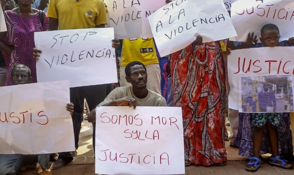 Inmigrantes senegaleses muestran pancartas contra la los Mossos D'esquadra en la manifestació en Salou para protestar por la muerte de un compatriota en una operación contra el 'top manta'. AFP PHOTO / QUIQUE GARCIA