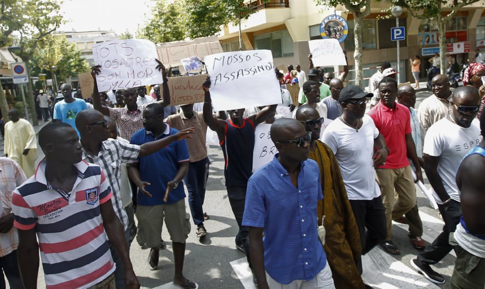 Inmigrantes senegaleses muestran pancartas contra la los Mossos D'esquadra en la manifestació en Salou para protestar por la muerte de un compatriota en una operación contra el 'top manta'. AFP PHOTO / QUIQUE GARCIA